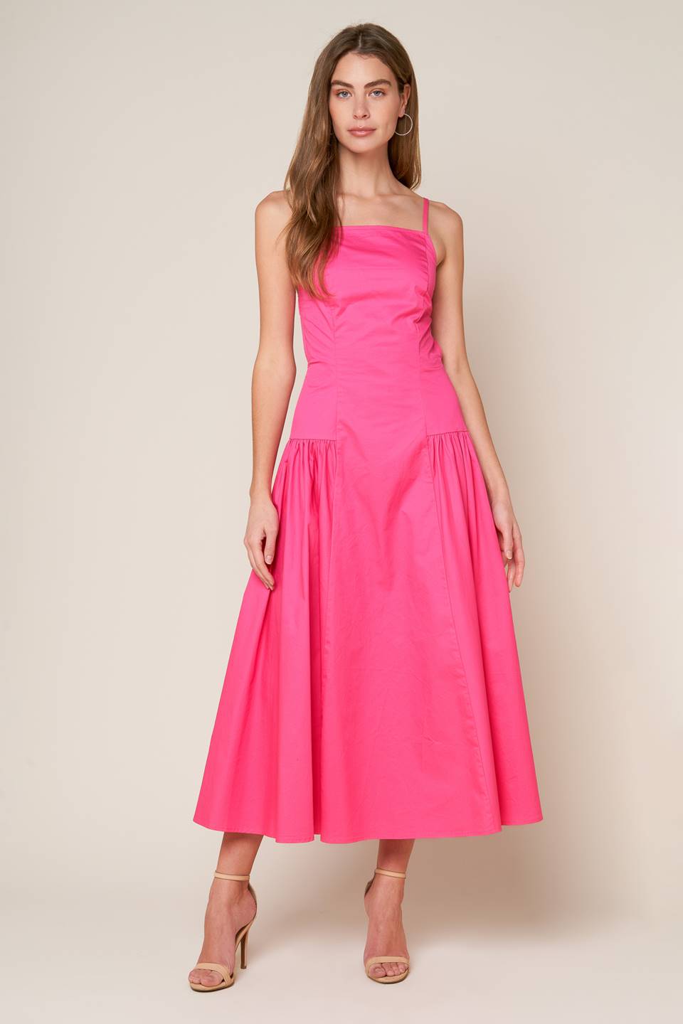 A midi dress with a solid woven fabric, sweetheart neckline, straps, and a full skirt with shirring on the sides. The back is open with a strap and zipper closure.