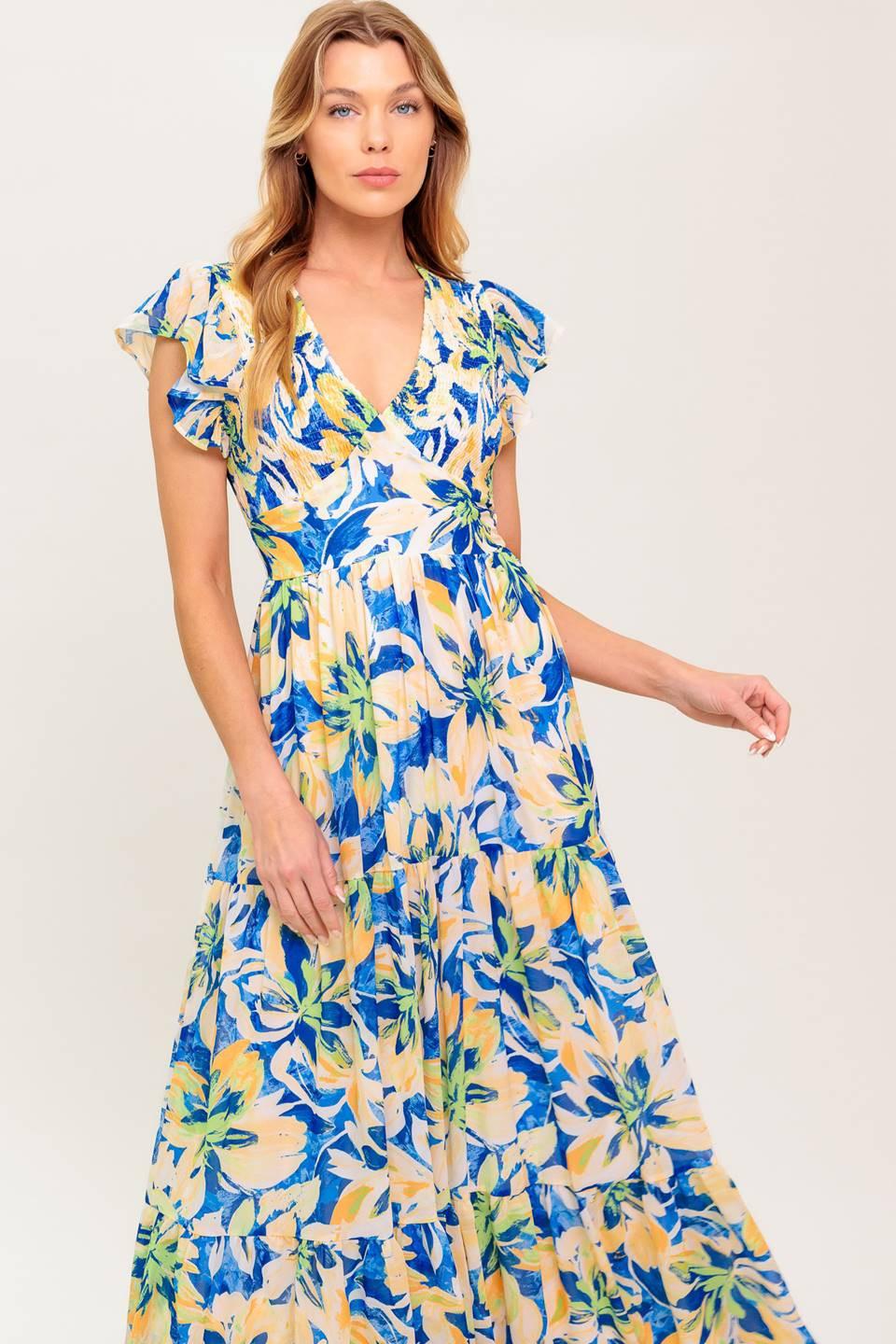 A printed woven maxi dress featuring V neckline, short flutter sleeve, smocked bodice, waist yoke and tiered skirt