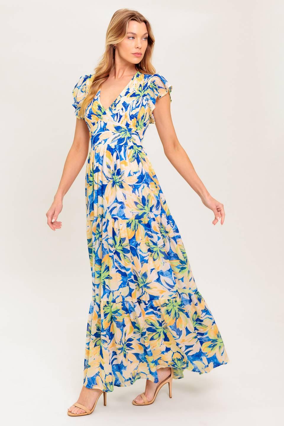 A printed woven maxi dress featuring V neckline, short flutter sleeve, smocked bodice, waist yoke and tiered skirt