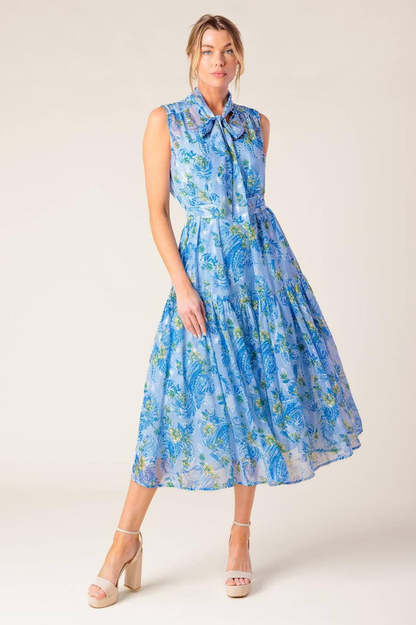 A printed woven midi dress featuring front bow tie, sleeveless, self belt and ruffled hemline