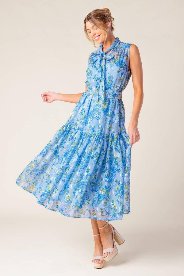A printed woven midi dress featuring front bow tie, sleeveless, self belt and ruffled hemline