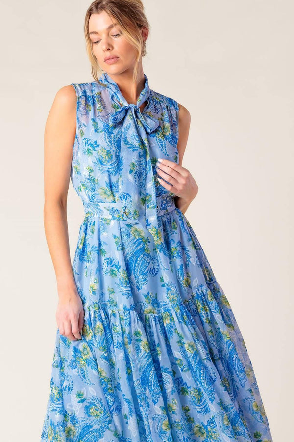 A printed woven midi dress featuring front bow tie, sleeveless, self belt and ruffled hemline