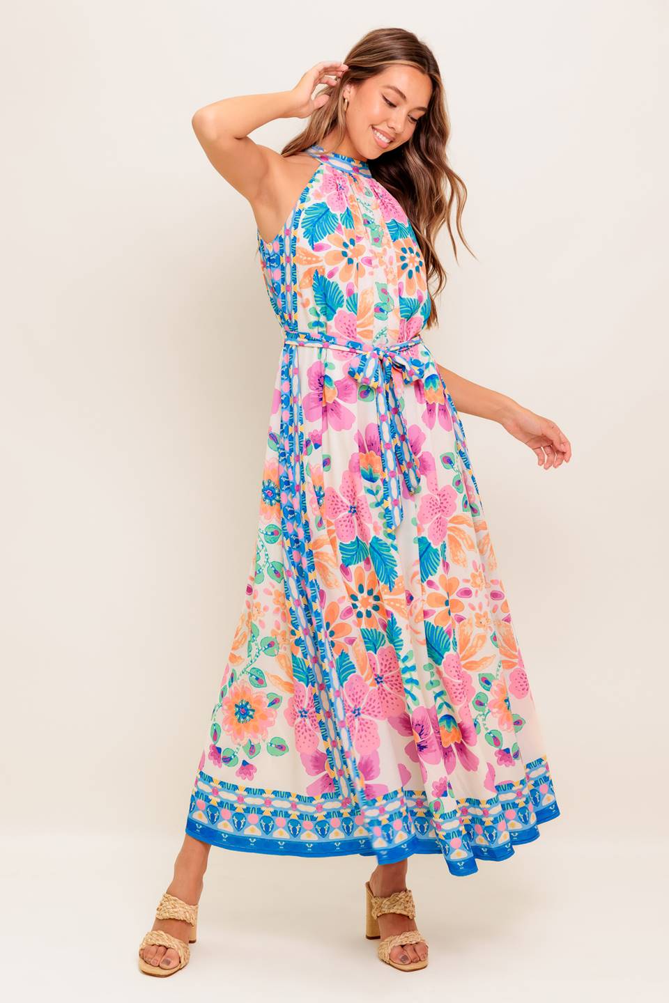 A printed woven maxi dress featuring halter neckline, self sash tie and back button closure.