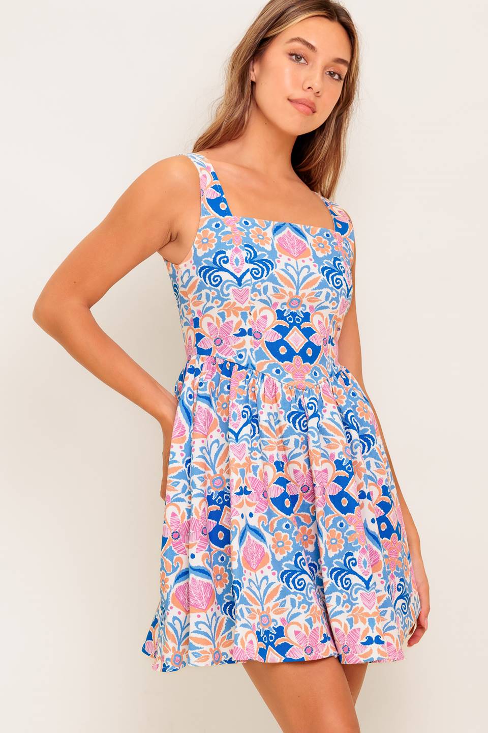 A printed woven mini dress featuring square neckline, sleeveless, basque waist, full skirt and back zipper closure