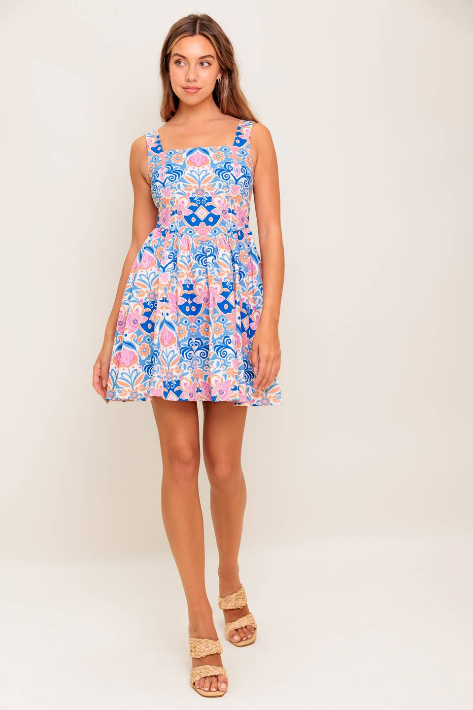 A printed woven mini dress featuring square neckline, sleeveless, basque waist, full skirt and back zipper closure