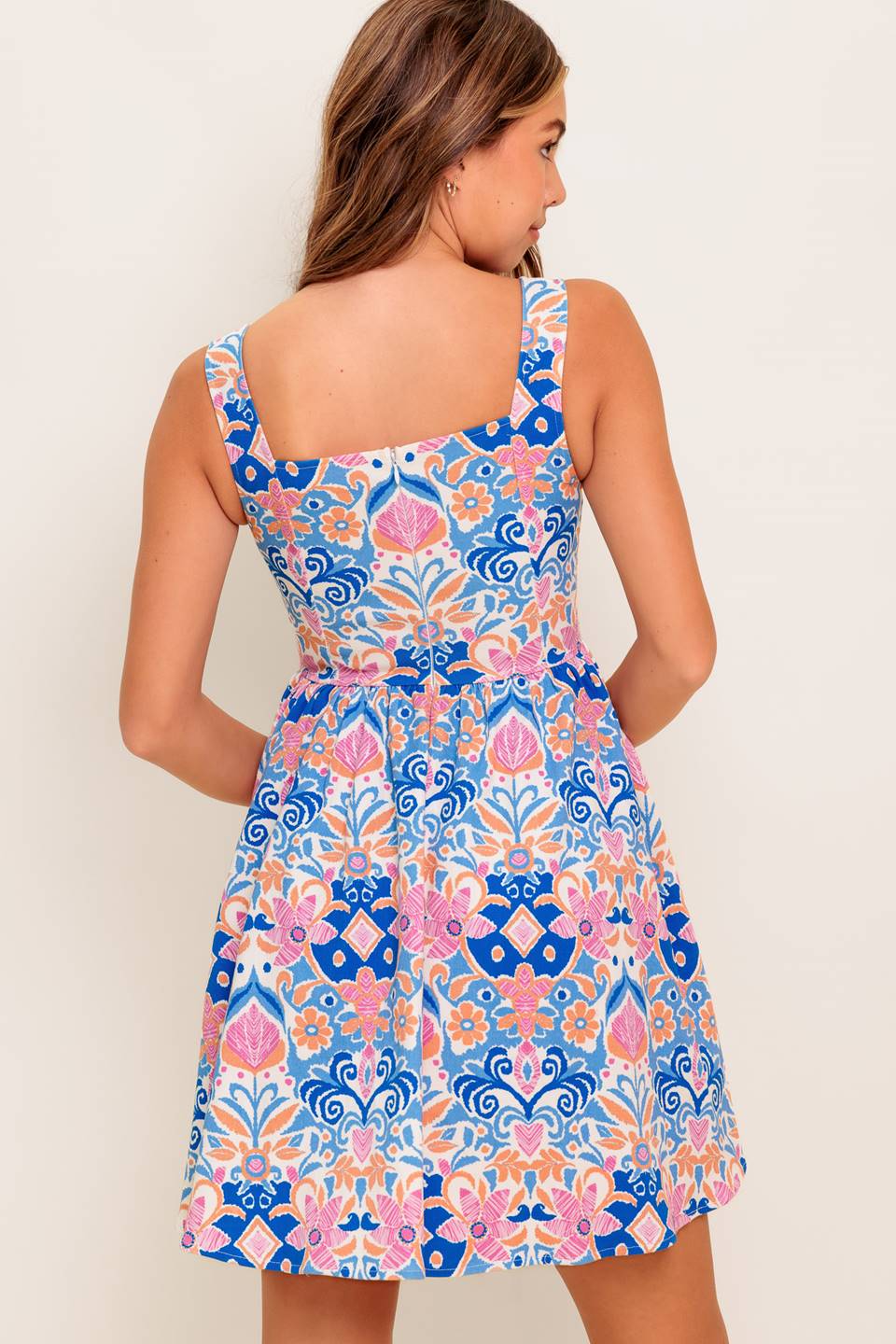 A printed woven mini dress featuring square neckline, sleeveless, basque waist, full skirt and back zipper closure