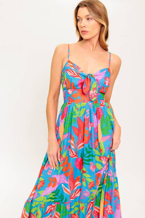 A printed woven dress featuring cami bodice with front tie detail, straps, ruffled hem and smocked back waist band