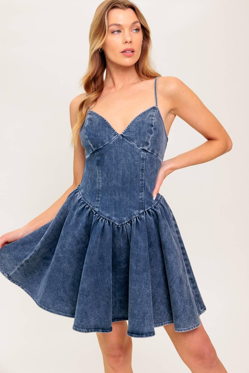 A washed denim mini dress featuring cami top, straps, basque waist line, low back and zipper closure