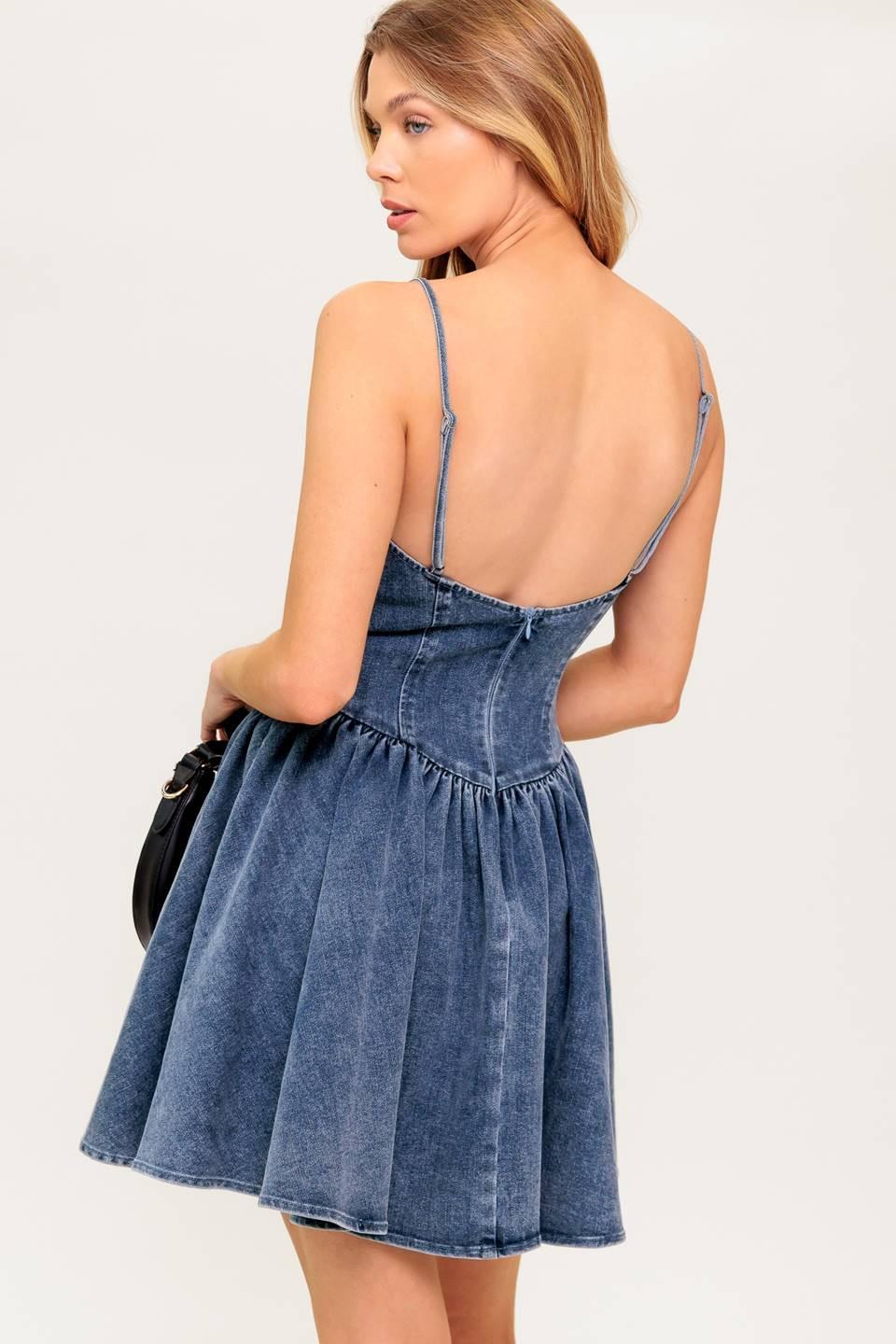 A washed denim mini dress featuring cami top, straps, basque waist line, low back and zipper closure