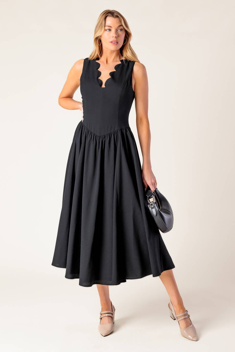 A solid black woven midi dress featuring V neckline with scalloped edge, sleeveless, full skirt and back zipper closure