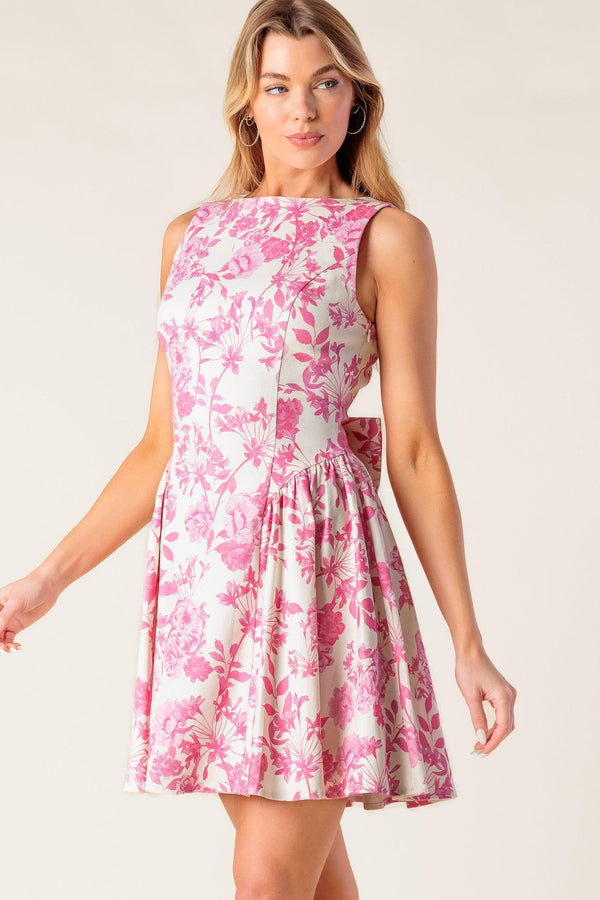 A printed woven mini dress featuring boat neckline, sleeveless, shirred side panel, bare back with bow detail and side zipper closure