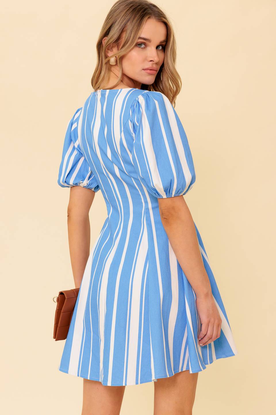 A blue and white stripe, printed woven mini dress featuring wide round neckline, short puff sleeve, front button down detail and back zipper closure