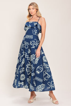Woman wearing a navy blue midi dress with fruit and beach elements printed; featuring straight neckline with flounce, straps, circle skirt and back zipper closure | Flying Tomato