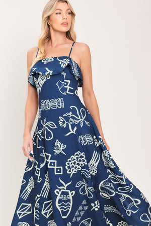 Woman wearing a navy blue midi dress with fruit and beach elements printed; featuring straight neckline with flounce, straps, circle skirt and back zipper closure | Flying Tomato