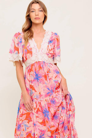 A printed woven maxi dress featuring lace trimmed V neckline, short flutter sleeve with lace hem, lace waistband, tiered skirt and smocked back waistband.