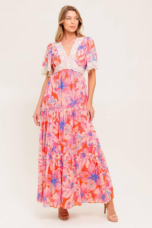 A printed woven maxi dress featuring lace trimmed V neckline, short flutter sleeve with lace hem, lace waistband, tiered skirt and smocked back waistband.