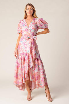 A printed woven hi-lo midi dress featuring surplice neckline, short puff sleeve, self sash tie and ruffled hemline