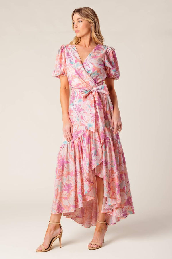 A printed woven hi-lo midi dress featuring surplice neckline, short puff sleeve, self sash tie and ruffled hemline