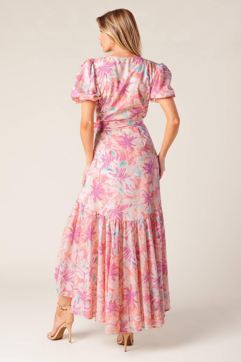 A printed woven hi-lo midi dress featuring surplice neckline, short puff sleeve, self sash tie and ruffled hemline