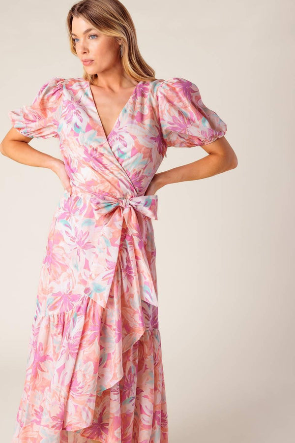 A printed woven hi-lo midi dress featuring surplice neckline, short puff sleeve, self sash tie and ruffled hemline