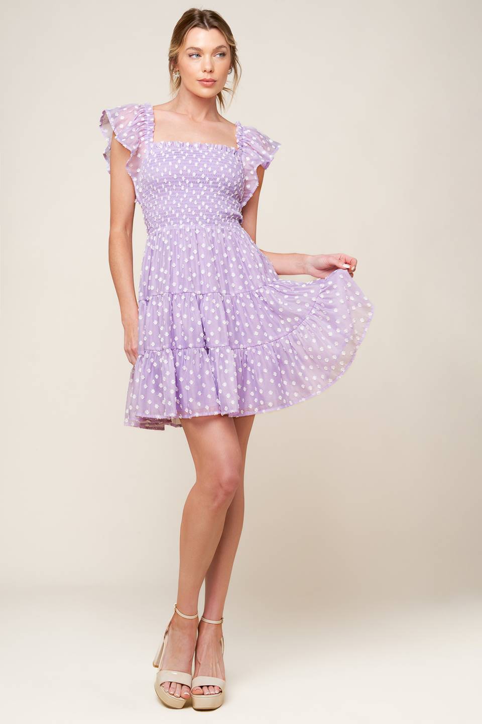 A textured lavender woven mini dress featuring square neckline, ruffled sleeve, smocked bodice and tiered skirt.