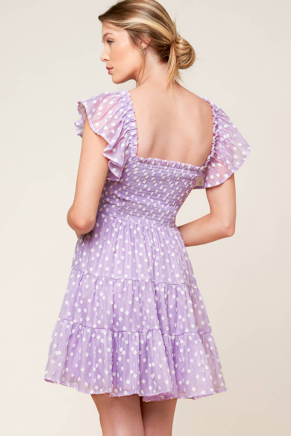 A textured lavender woven mini dress featuring square neckline, ruffled sleeve, smocked bodice and tiered skirt.