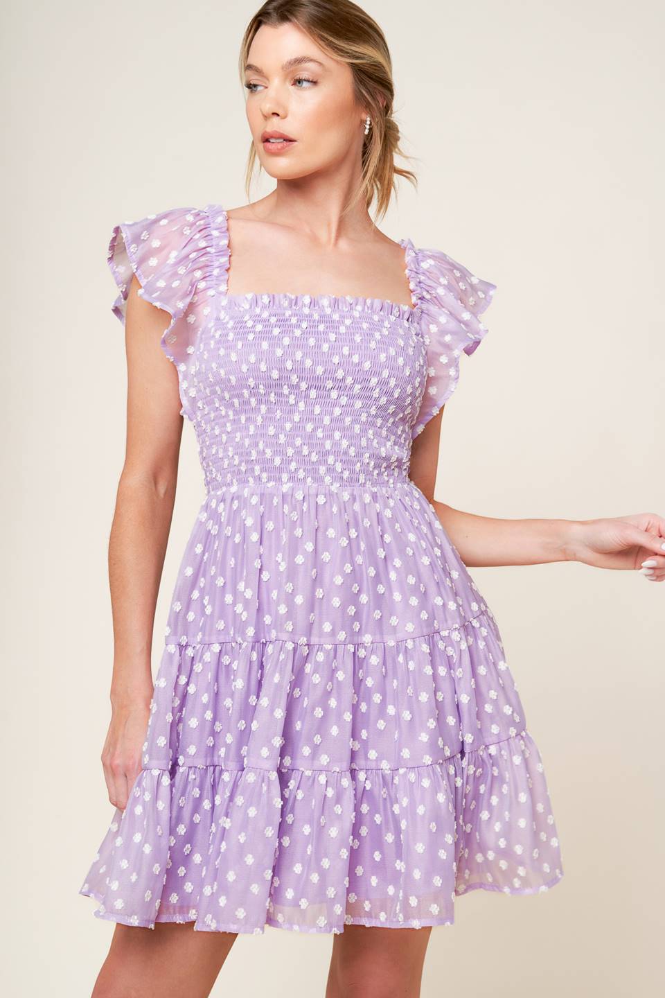 A textured lavender woven mini dress featuring square neckline, ruffled sleeve, smocked bodice and tiered skirt.