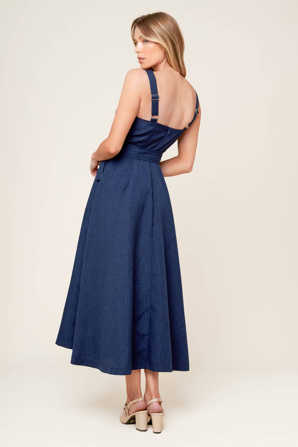 A solid woven midi dress featuring straight neckline, straps, self belt, side pockets, full skirt and back zipper closure