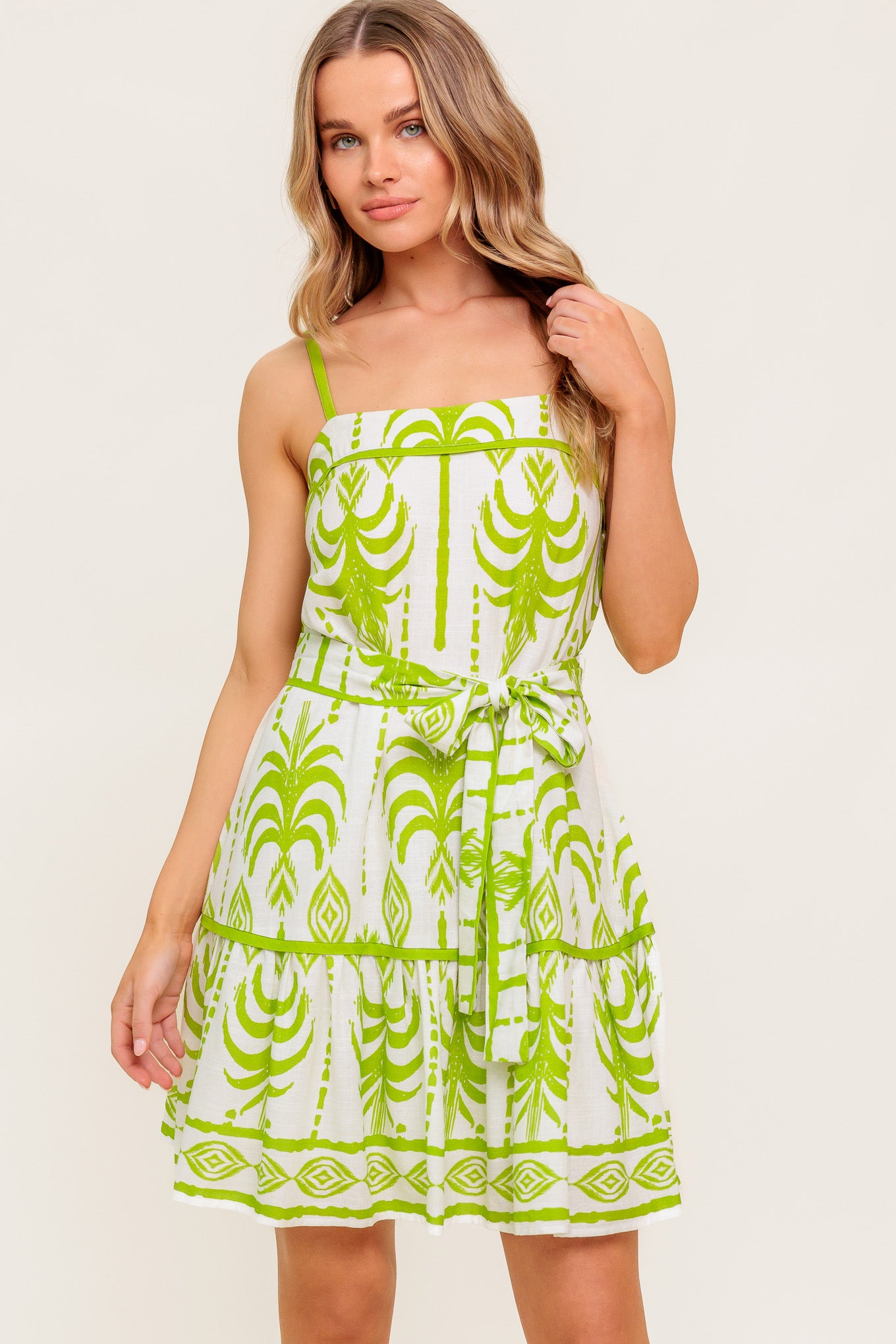A printed woven mini dress featuring straight neckline, straps, self sash tie and ruffled hemline.