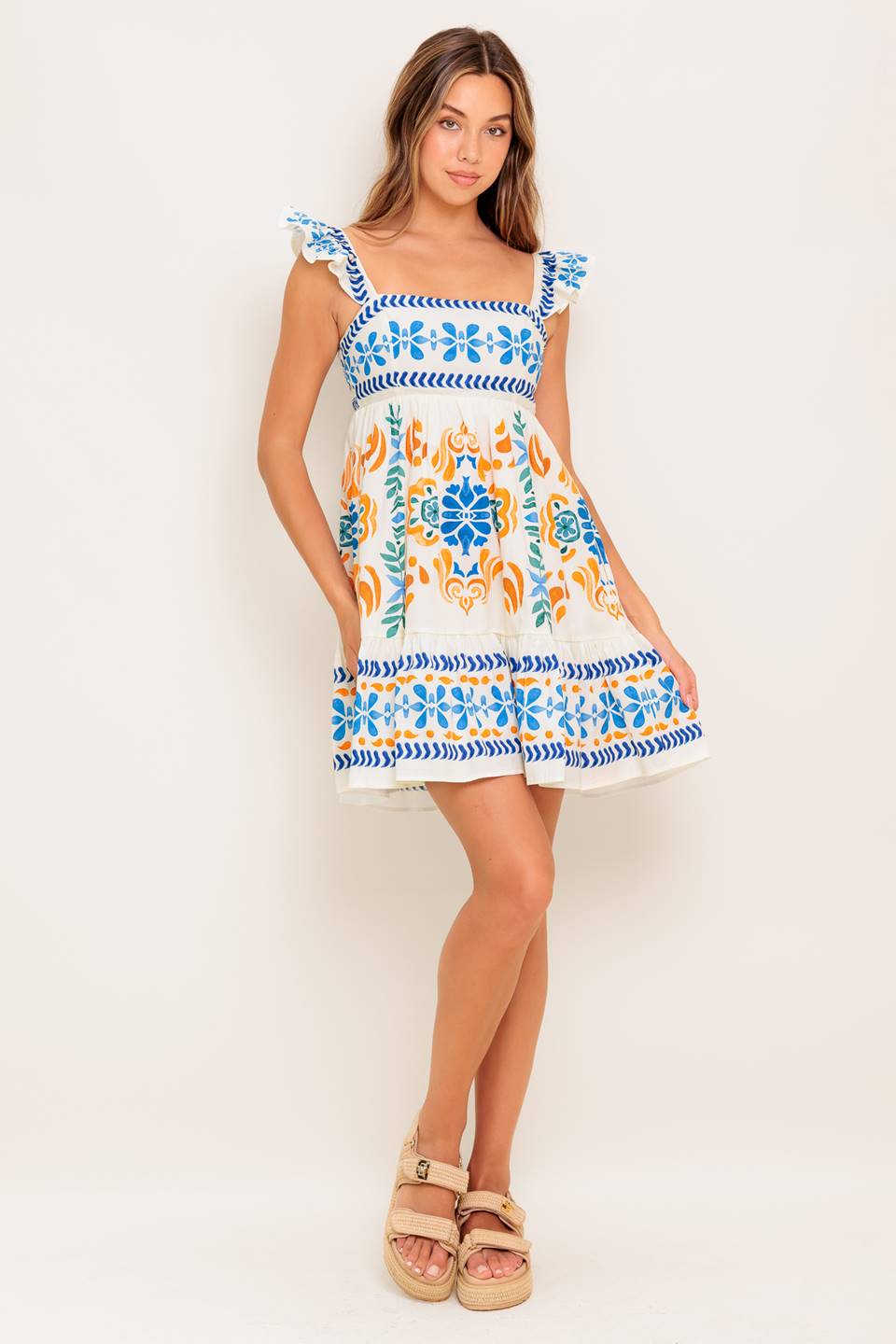 A printed woven mini dress featuring square neckline, ruffled sleeve, ruffled hemline and smocked back bodice