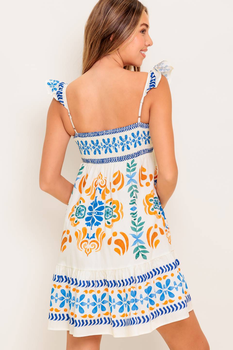 A printed woven mini dress featuring square neckline, ruffled sleeve, ruffled hemline and smocked back bodice