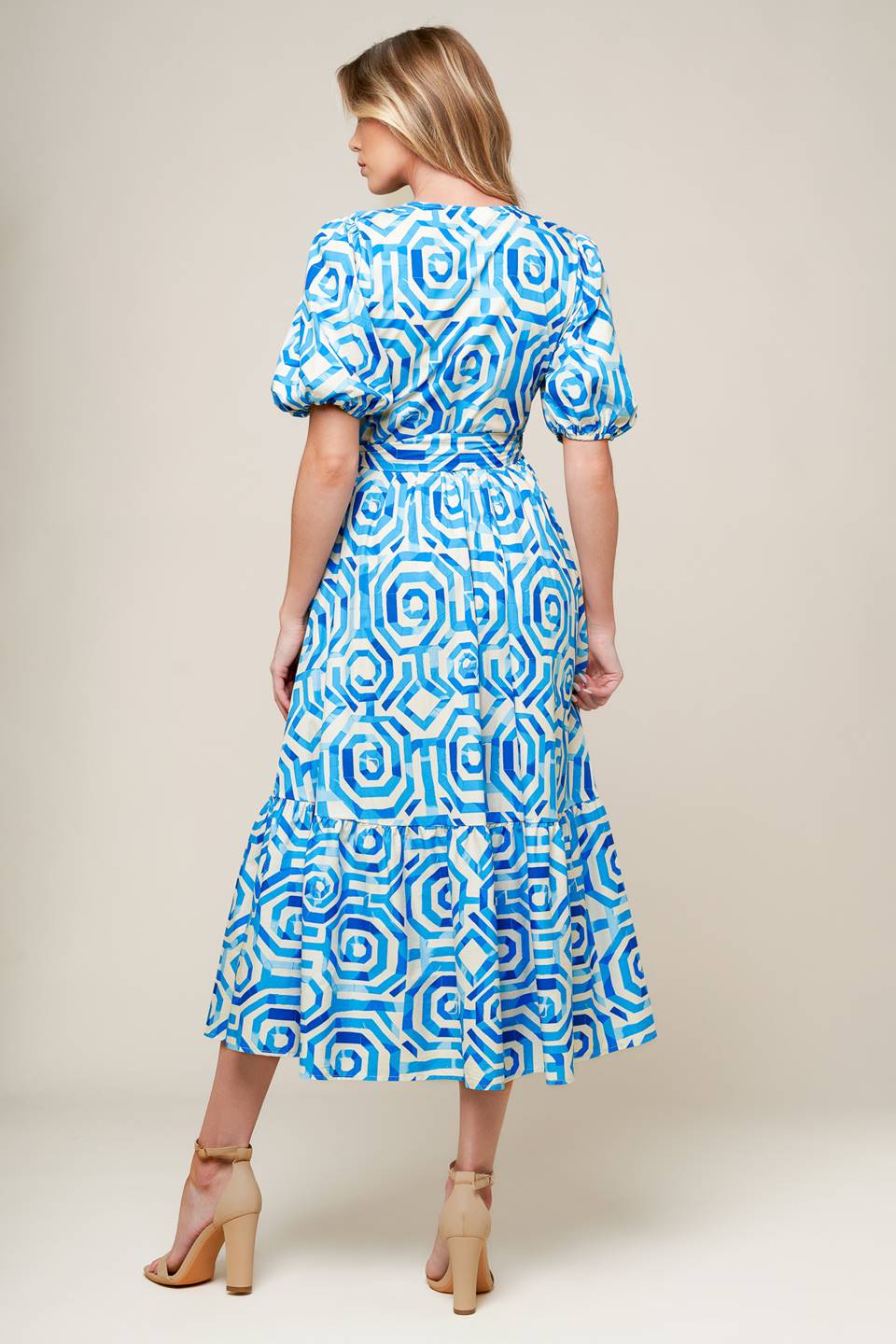 A printed blue and white woven midi dress featuring surplice neckline, short puff sleeve, true wrap with side tie and ruffled hemline.