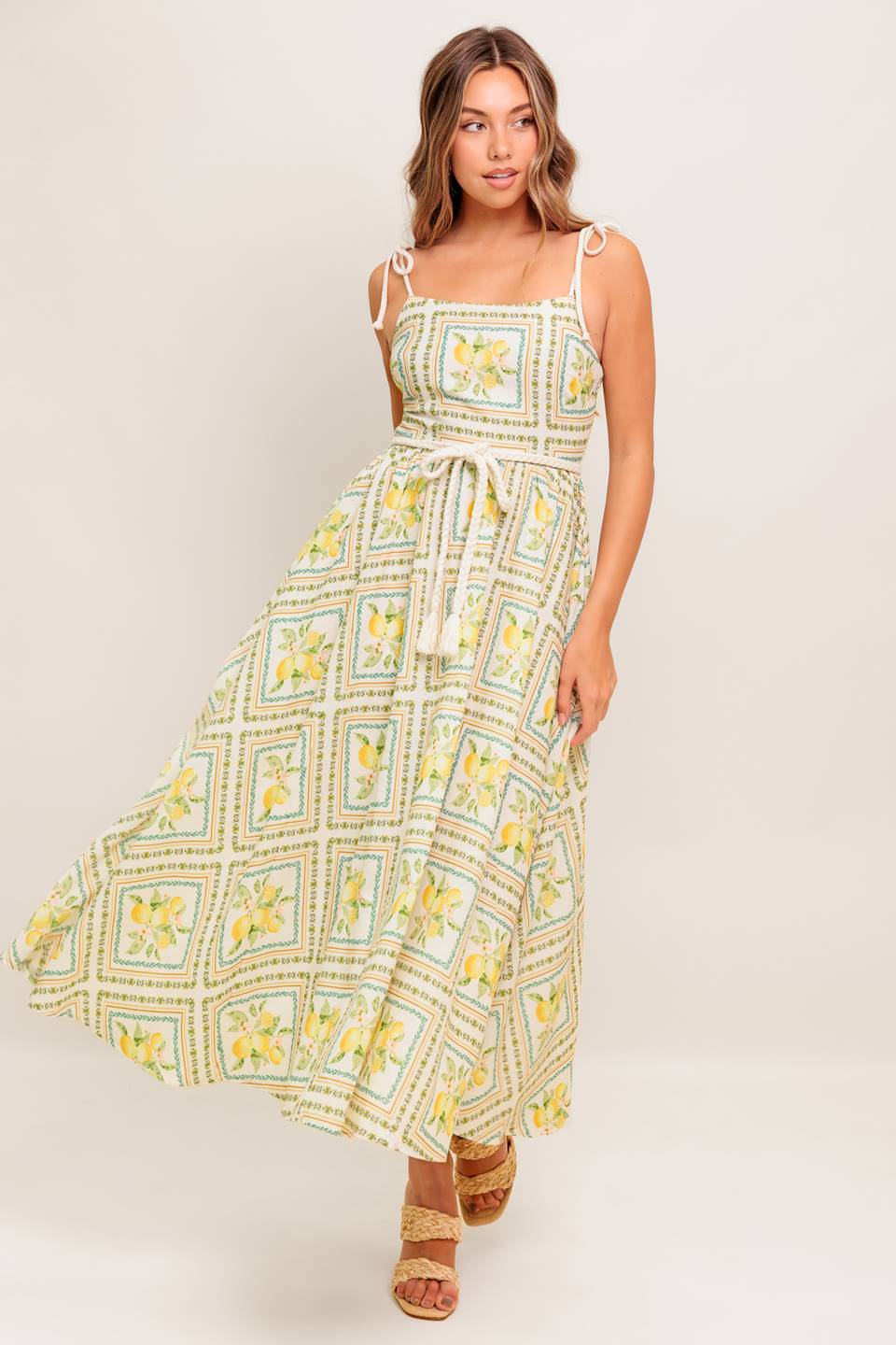 A printed woven midi dress featuring straight neckline, braided straps and belt, circle skirt and smocked back bodice
