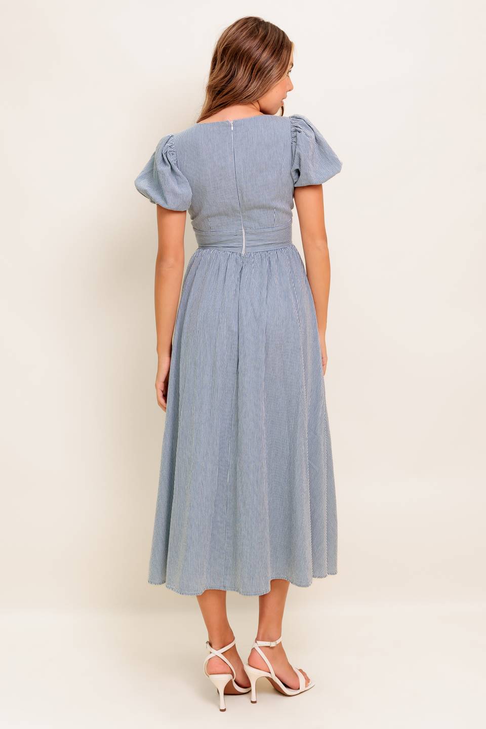 A striped woven midi dress featuring round neckline, front bow ties, short puff sleeve, waist yoke, full skirt and back zipper closure.
