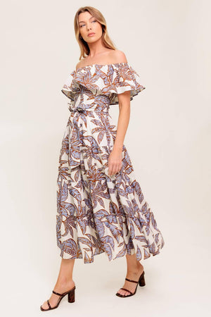 A printed woven midi dress featuring off shoulder neckline, flounce, elasticized waist with self sash tie and tiered skirt.