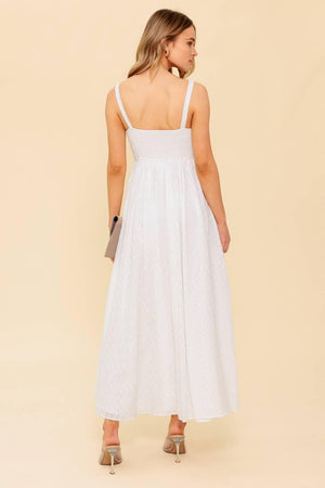 A solid white eyelet midi dress featuring sweetheart neckline, straps, full skirt and smocked back bodice