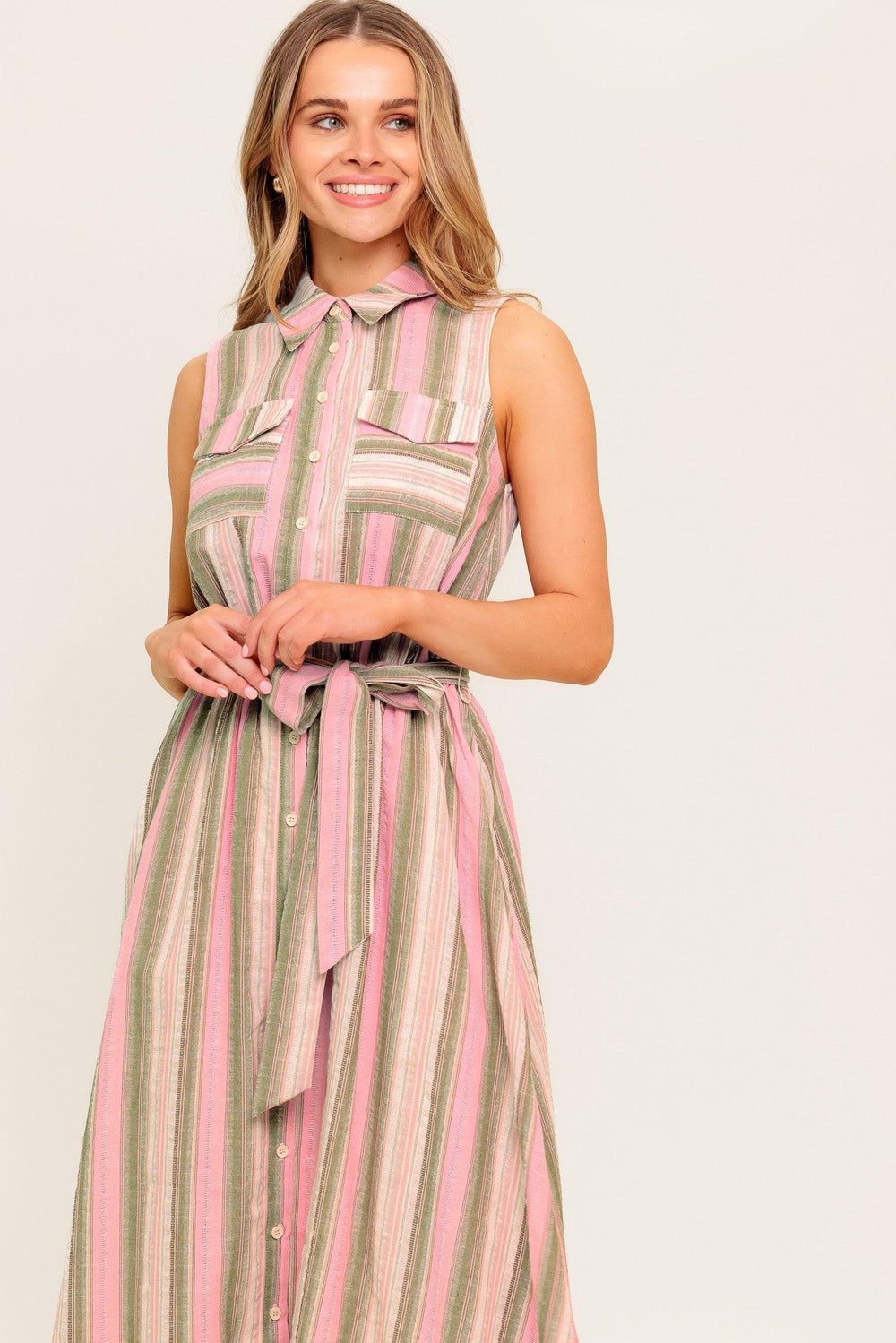 A striped woven midi dress featuring collar, button down, pockets, elasticized waist, self sash and full skirt.