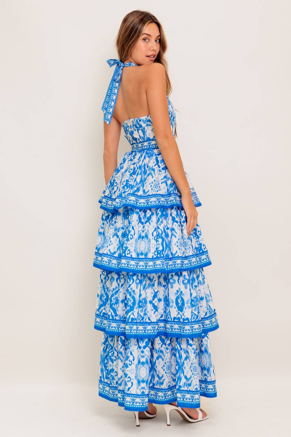 A printed woven maxi dress featuring halter neckline, sleeveless, layered skirt and back zipper closure