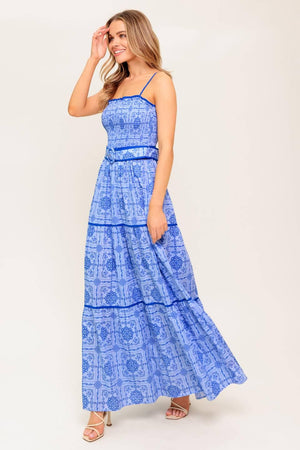 A printed woven maxi dress featuring straight neckline, straps, smocked bodice, self belt and tiered skirt.