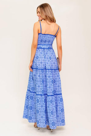 A printed woven maxi dress featuring straight neckline, straps, smocked bodice, self belt and tiered skirt.