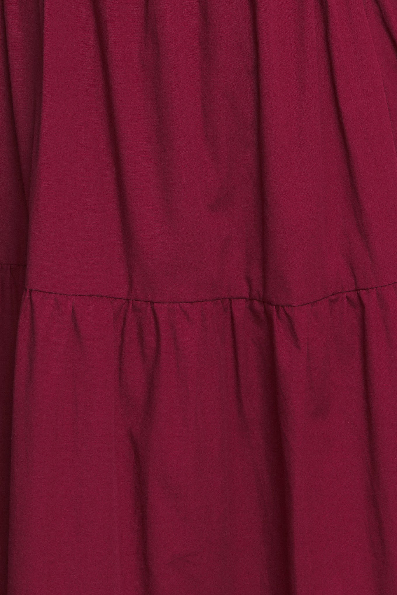 A solid woven maxi dress featuring V neckline with front bow closure, short puff sleeve, elasticized empire and tiered skirt.