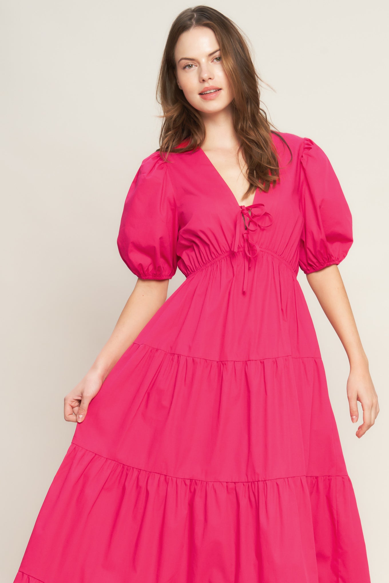 Woman wearing a bright pink dress with puff sleeves on a plain background - FLYING TOMATO