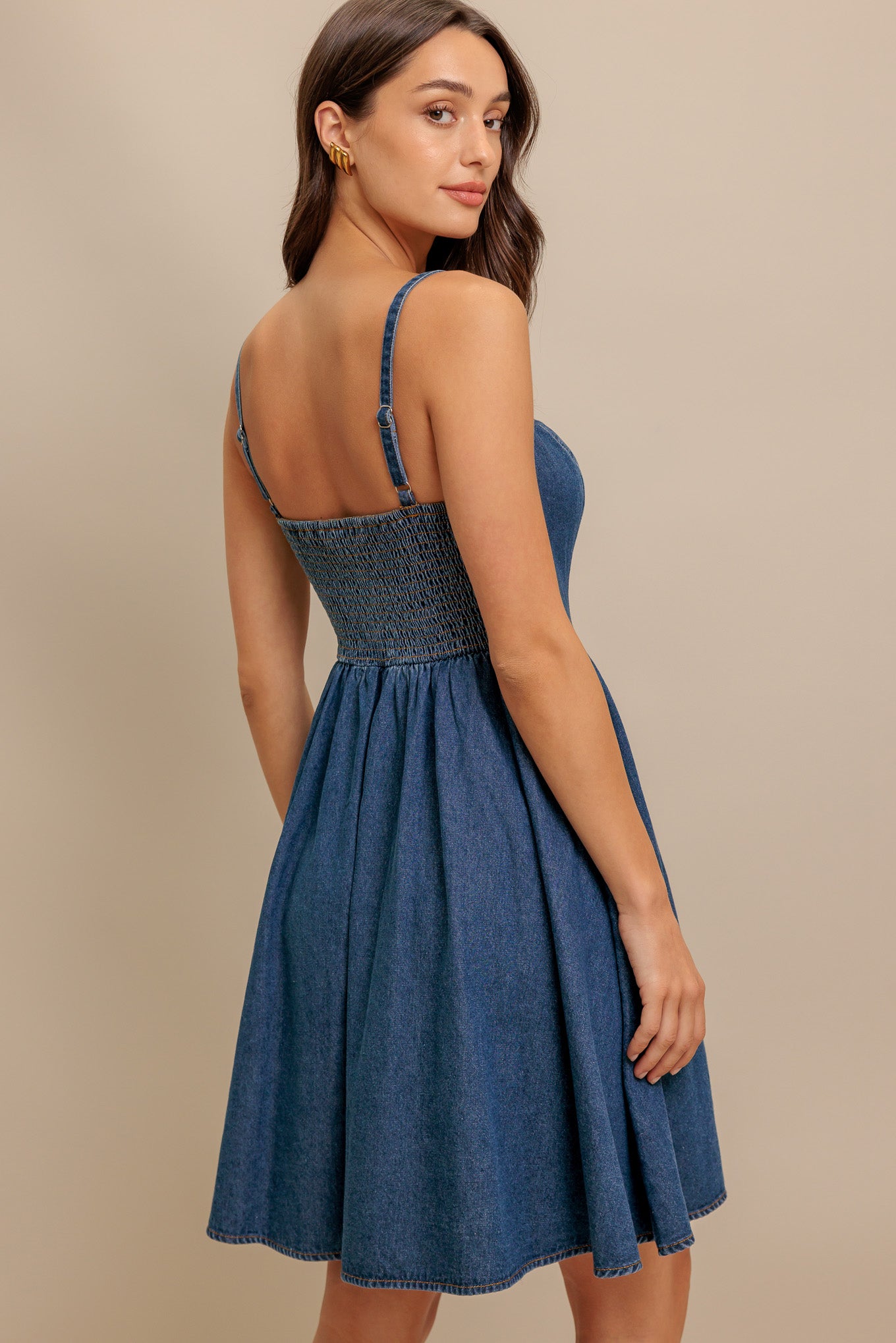 A washed denim mini dress featuring straight neckline, straps, front lace up detail, basque waistline, full skirt and smocked back bodice
