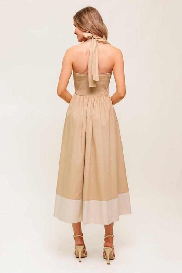 A solid woven midi dress featuring sweetheart neckline with gathered front, halter tie, full skirt and smocked back bodice.
