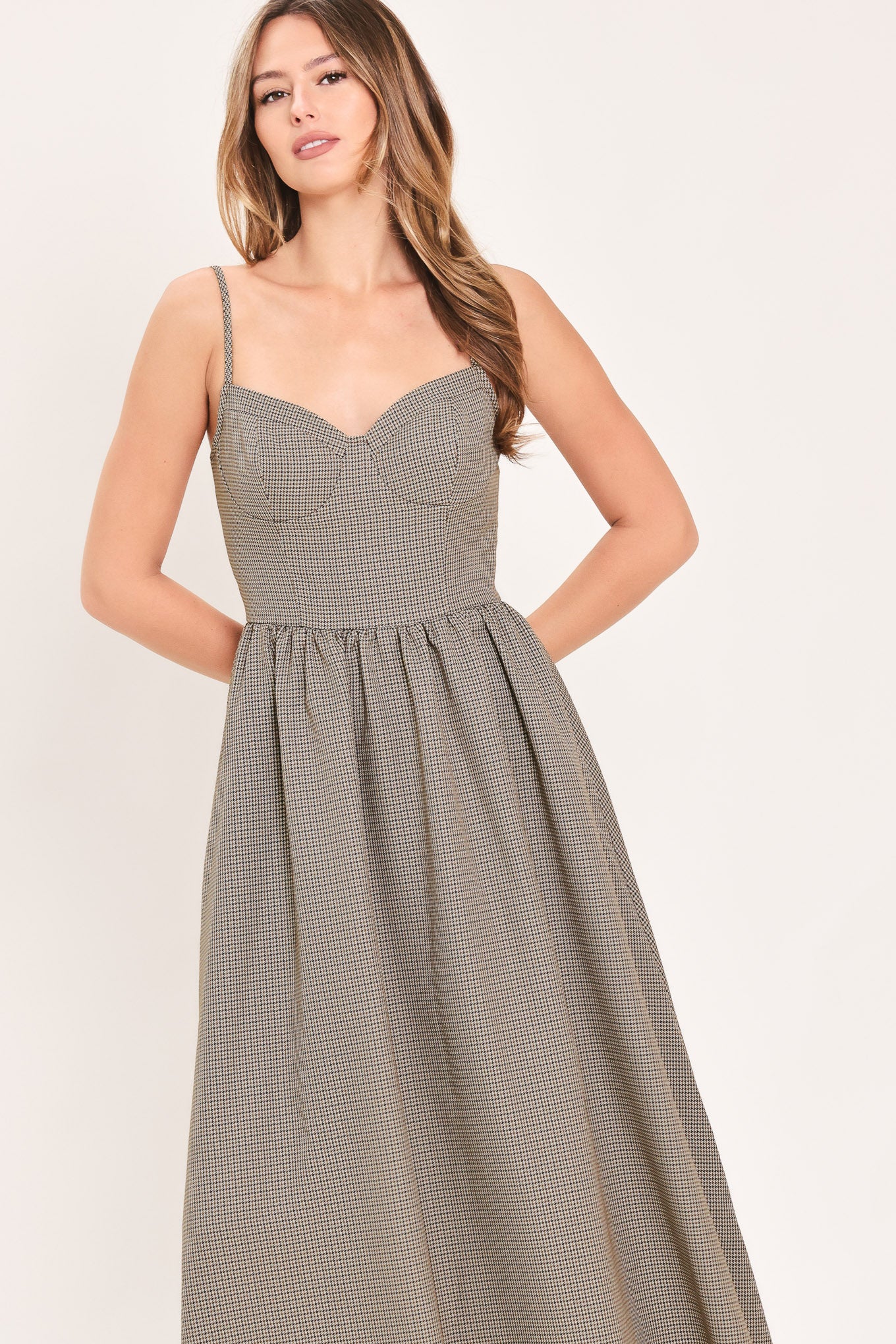A woman wearing a plaid taupe and brown spaghetti strap midi dress | Flying Tomato