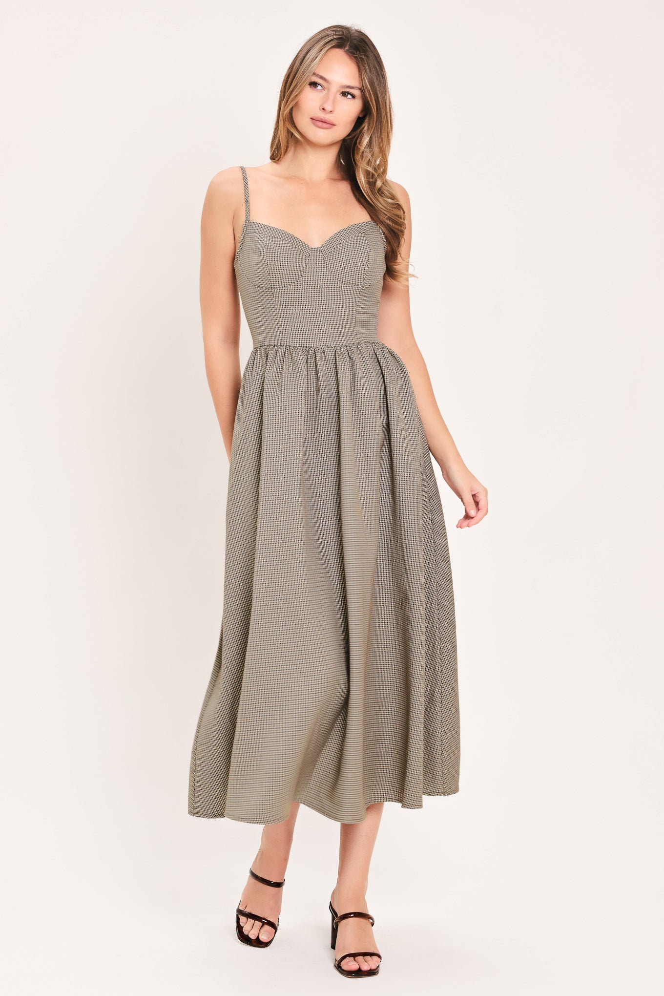 A woman wearing a plaid taupe and brown spaghetti strap midi dress | Flying Tomato
