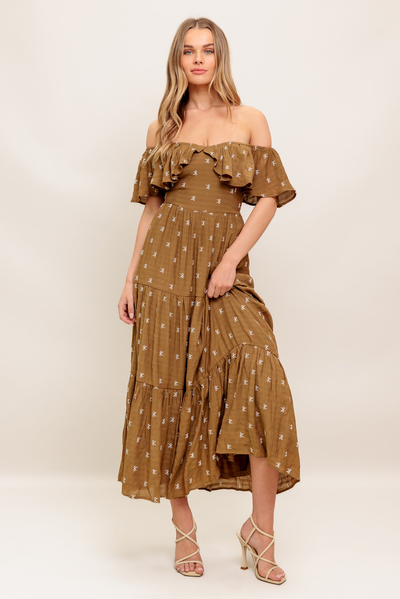 A textured embroidered woven midi dress featuring off shoulder neckline with flounce, tiered skirt and smocked back bodice