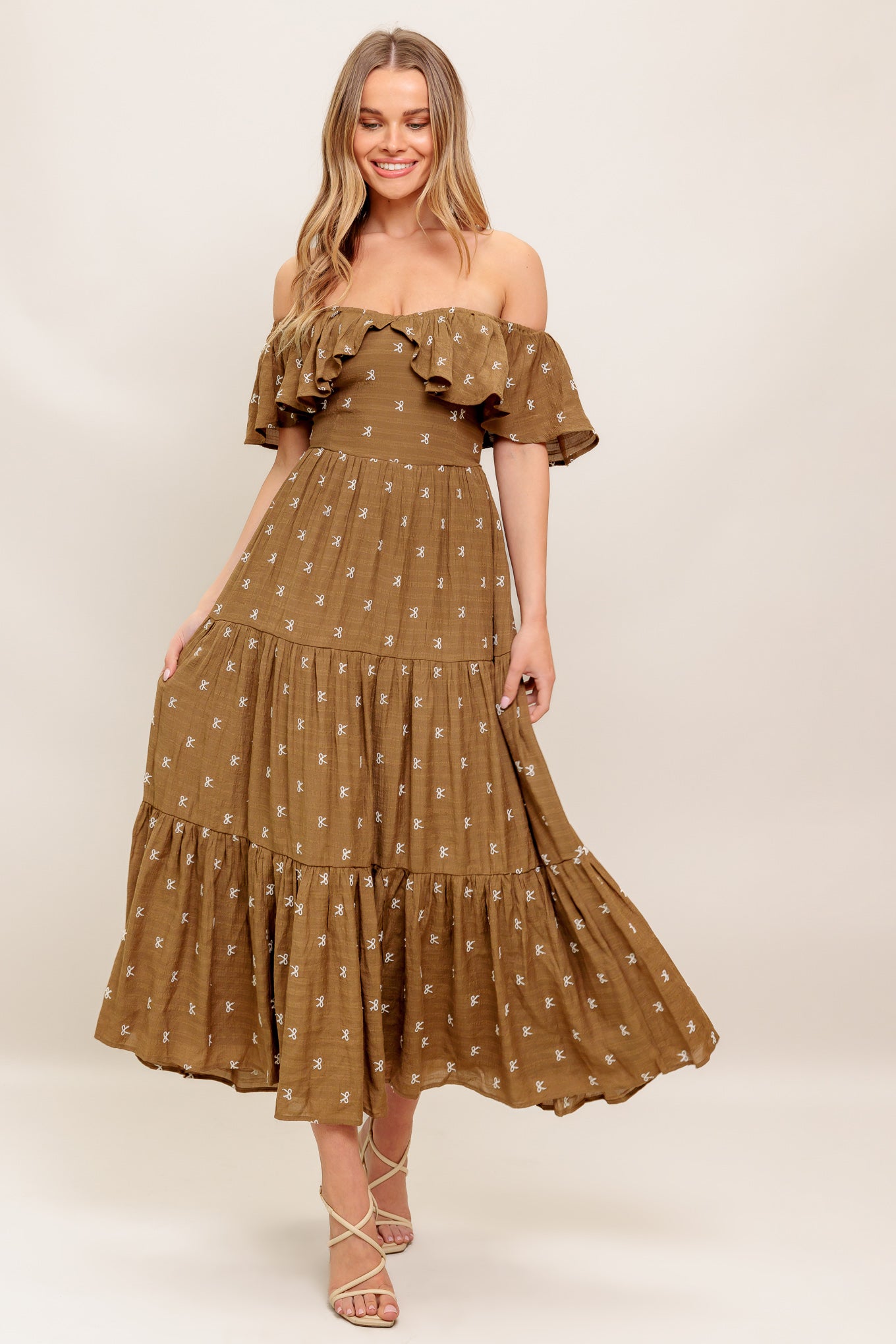 A textured embroidered woven midi dress featuring off shoulder neckline with flounce, tiered skirt and smocked back bodice
