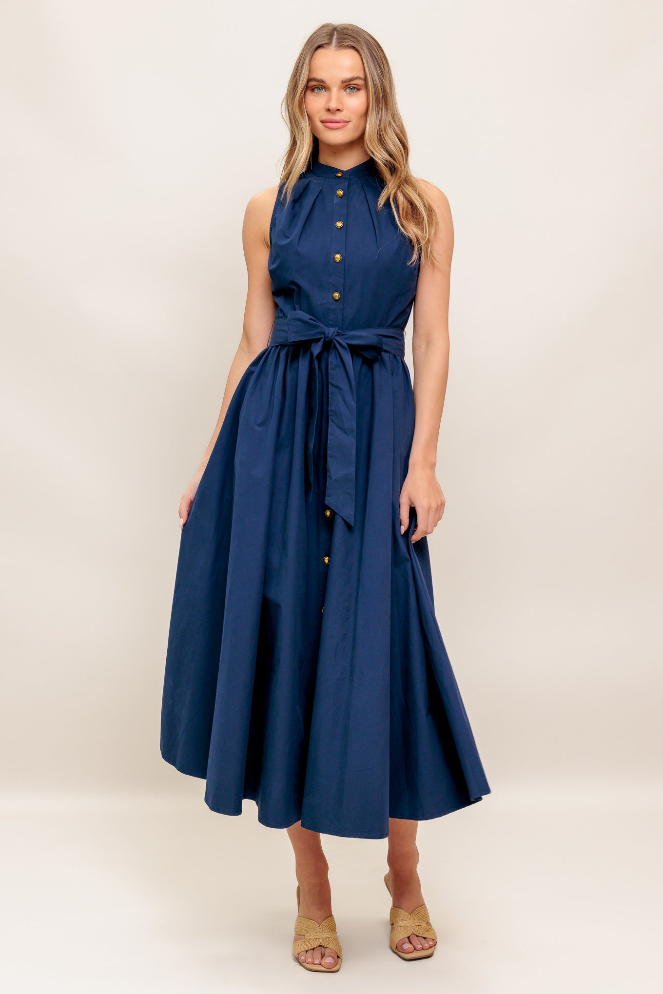 A solid navy woven midi dress featuring high neckline, sleeveless, button down, self sash tie and full skirt