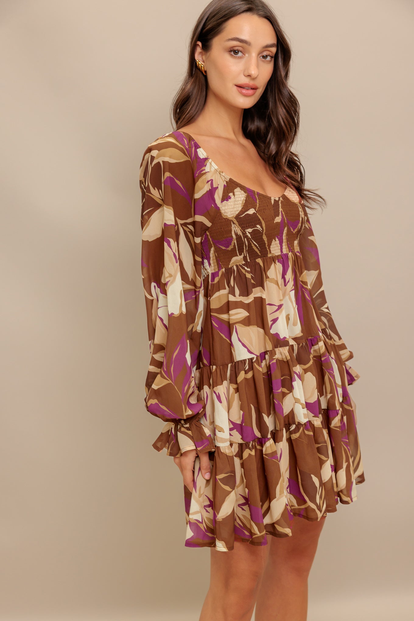A printed woven mini dress featuring U neckline, long sleeve with ruffled cuff, smocked bodice and tiered skirt